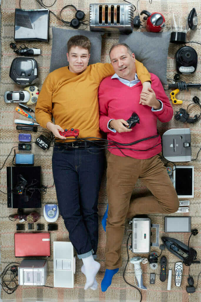 overhead shot of A light skinned man and a boy lying down amongst a lot of electrical goods