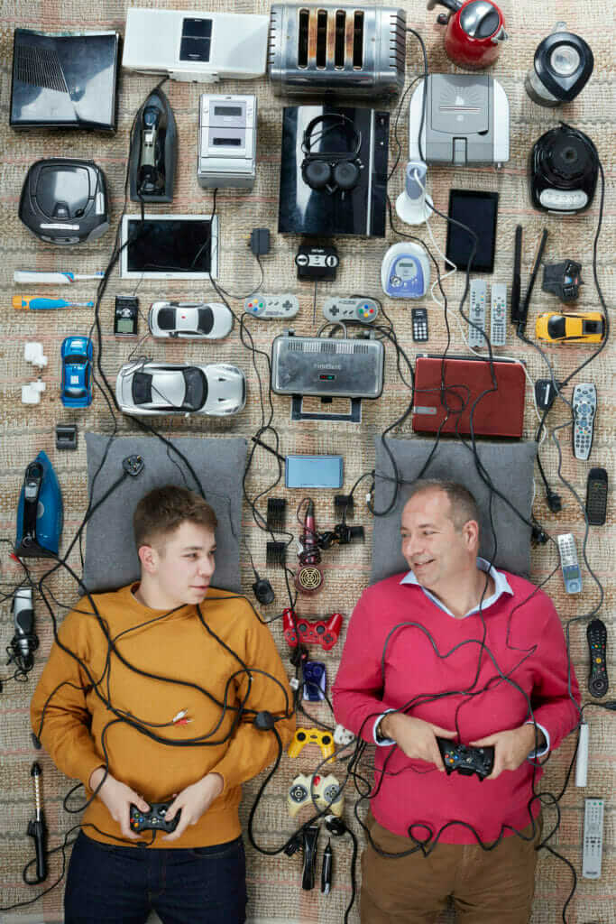 overhead shot of A light skinned man and a boy lying down amongst a lot of electrical goods