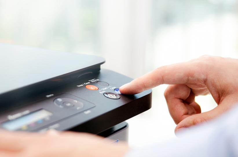 close up of a light skinned person pressing a button on the top of a printer