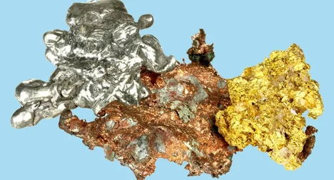 Lumps of molten silver, bronze, and gold melted together on a bright blue background.