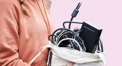 woman in a pink zip top holding a cloth bag of cables